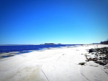 Scenic view of beach against clear blue sky