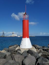 Lighthouse by sea against sky