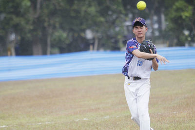 Portrait of baseball player throwing ball on field