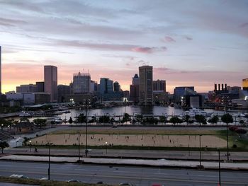 Modern buildings in city against sky during sunset