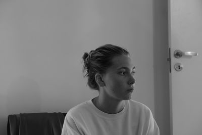 Teenage girl looking away against wall at home