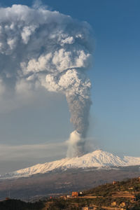 Smoke emitting from volcanic landscape against sky