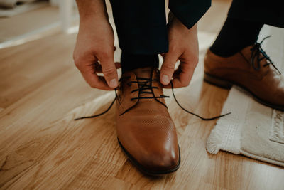 Low section of man wearing shoes on hardwood floor