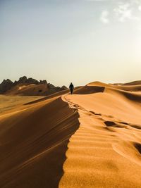 Man walking on desert against clear sky