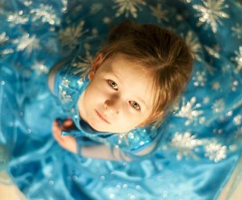 Directly above portrait of cute girl wearing blue dress sitting at home