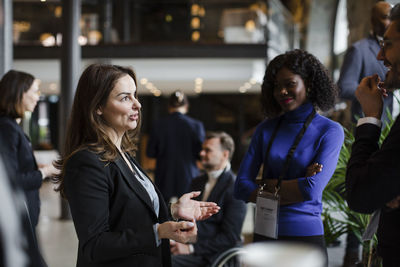 Businesswoman gesturing while discussing with delegates during seminar