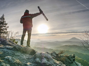 Tourist hold travel tripod. photographer climbed on peak for photographing the sunrise from mountain