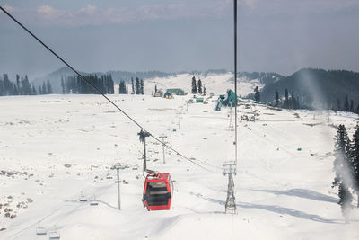 Overhead cable car on snow covered landscape against sky