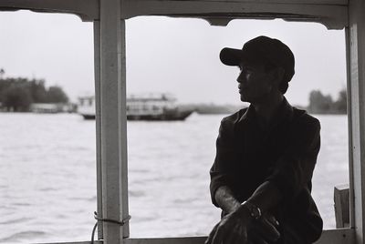 Man sitting on window against lake