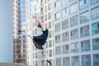 Side view of man jumping against building