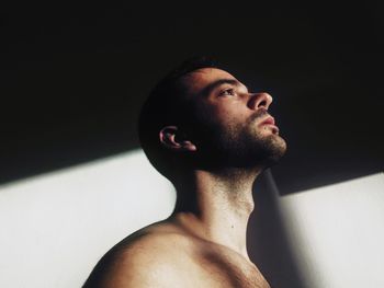 Portrait of young man looking away against black background