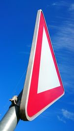 Low angle view of road sign against blue sky