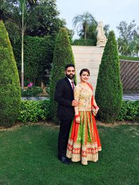 Portrait of smiling woman with arms raised against tree