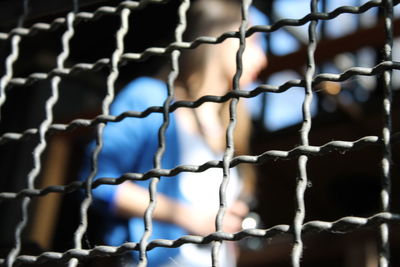 Woman seen through fence on sunny day