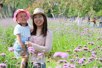 Full length of a smiling girl standing by flowering plants