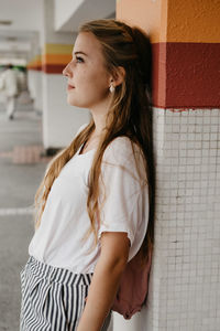 Young woman standing against wall