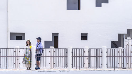 Full length of friends standing on railing against building