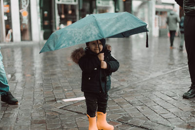 Cuty boy with an umbrella under the rain