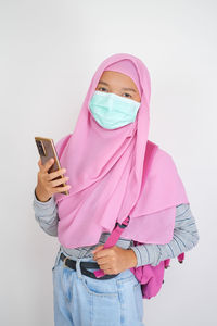 Midsection of woman holding smart phone against white background