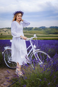 Portrait of young woman with bicycle against sky