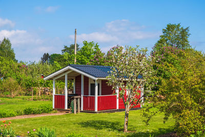 House and trees on field against sky