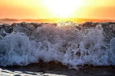 View of waves splashing in sea during sunset