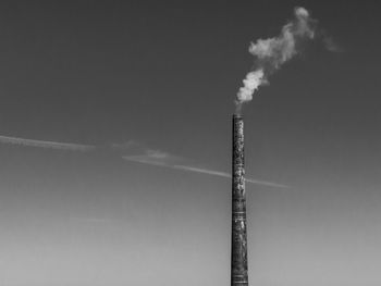 Low angle view of smoke emitting from chimney against sky