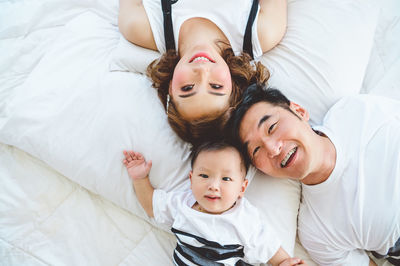 Portrait of happy friends lying on bed