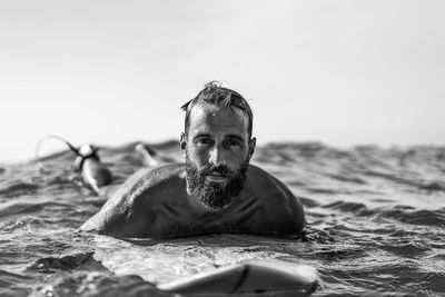 Portrait of shirtless man in sea against sky