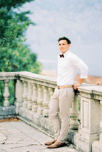 Portrait of young man standing against railing