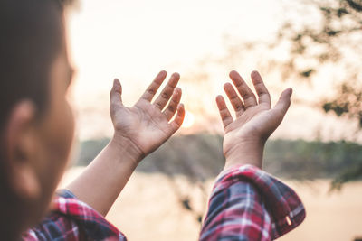 Close-up of hands against sky