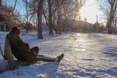 Man sitting on snow covered land