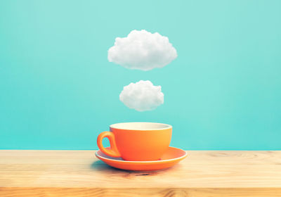 Close-up of coffee cup on table against blue sky