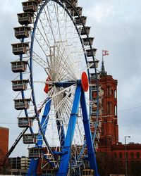 Low angle view of ferris wheel against cloudy sky