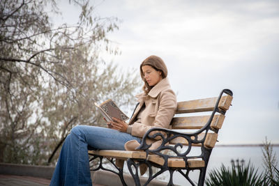 Young woman using laptop while sitting on bench