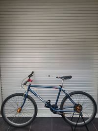 Bicycle parked on footpath against wall