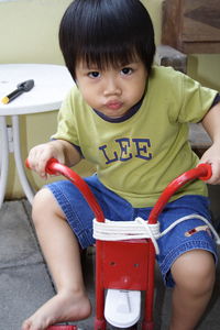 Cute smiling boy sitting on tricycle at home