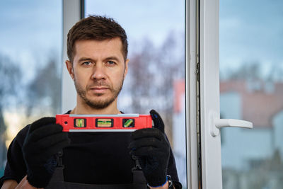 Portrait of young man standing by window