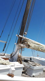 Low angle view of sailboats moored at harbor against clear blue sky