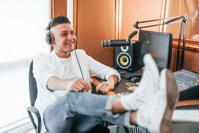 Talks and uses mic. young man is indoors in the radio studio is busy by broadcast.