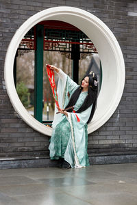 Rear view of woman standing against wall