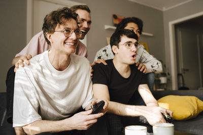 Happy male friends playing video game at home