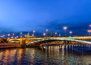 Illuminated bridge over river against sky at night