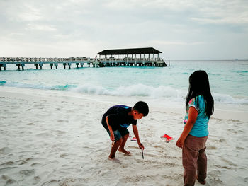 Children playing at beach against sky