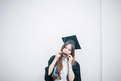 Portrait of young woman in graduation gown playing harmonica