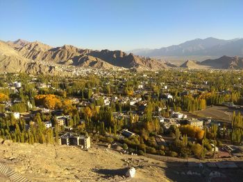 Scenic view of townscape by mountains against clear sky
