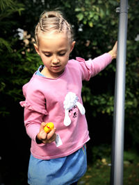 Girl standing with toy in hand outdoors