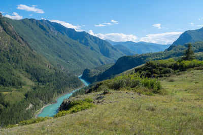 Alpine landscape of a valley with a turquoise river from the top of a mountain, a hill