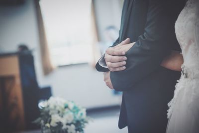 Midsection of couple holding hands at wedding ceremony