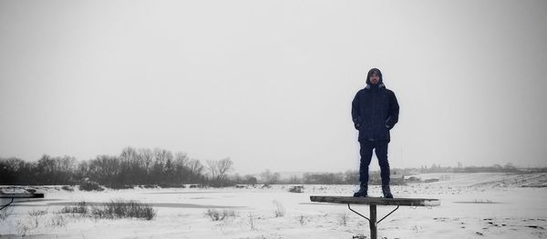 Rear view of man standing on snow covered field against sky